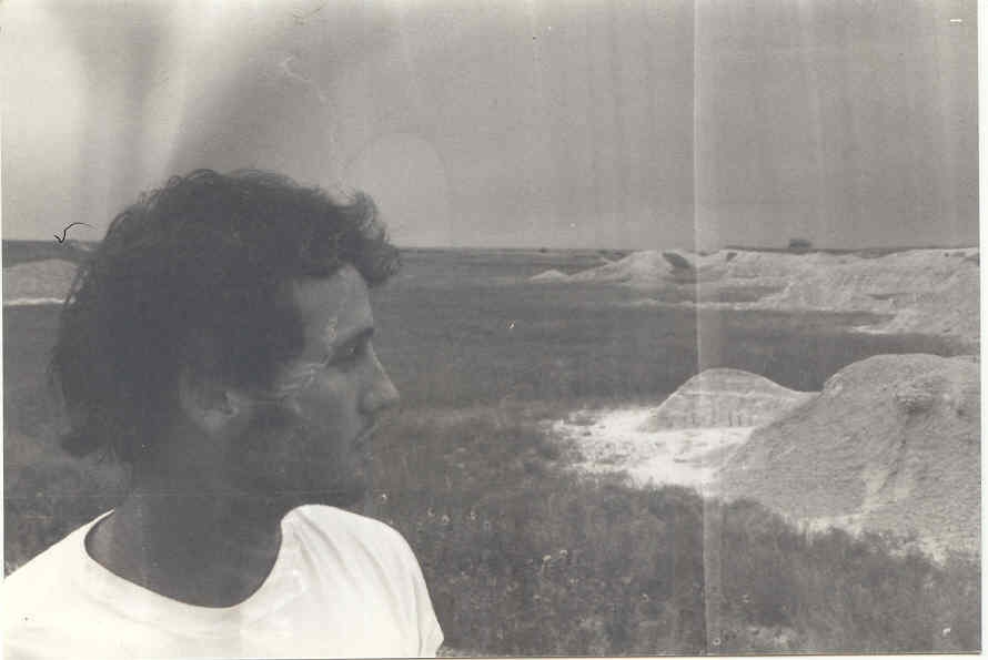 Black and white photograph featuring AJ looking out over sand dunes.