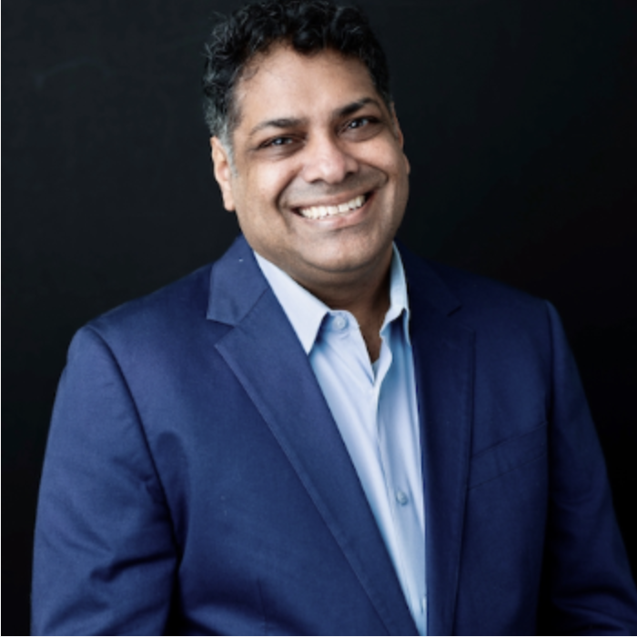 Color photograph of Manu Samriti Chander in a suit jacket and shirt.