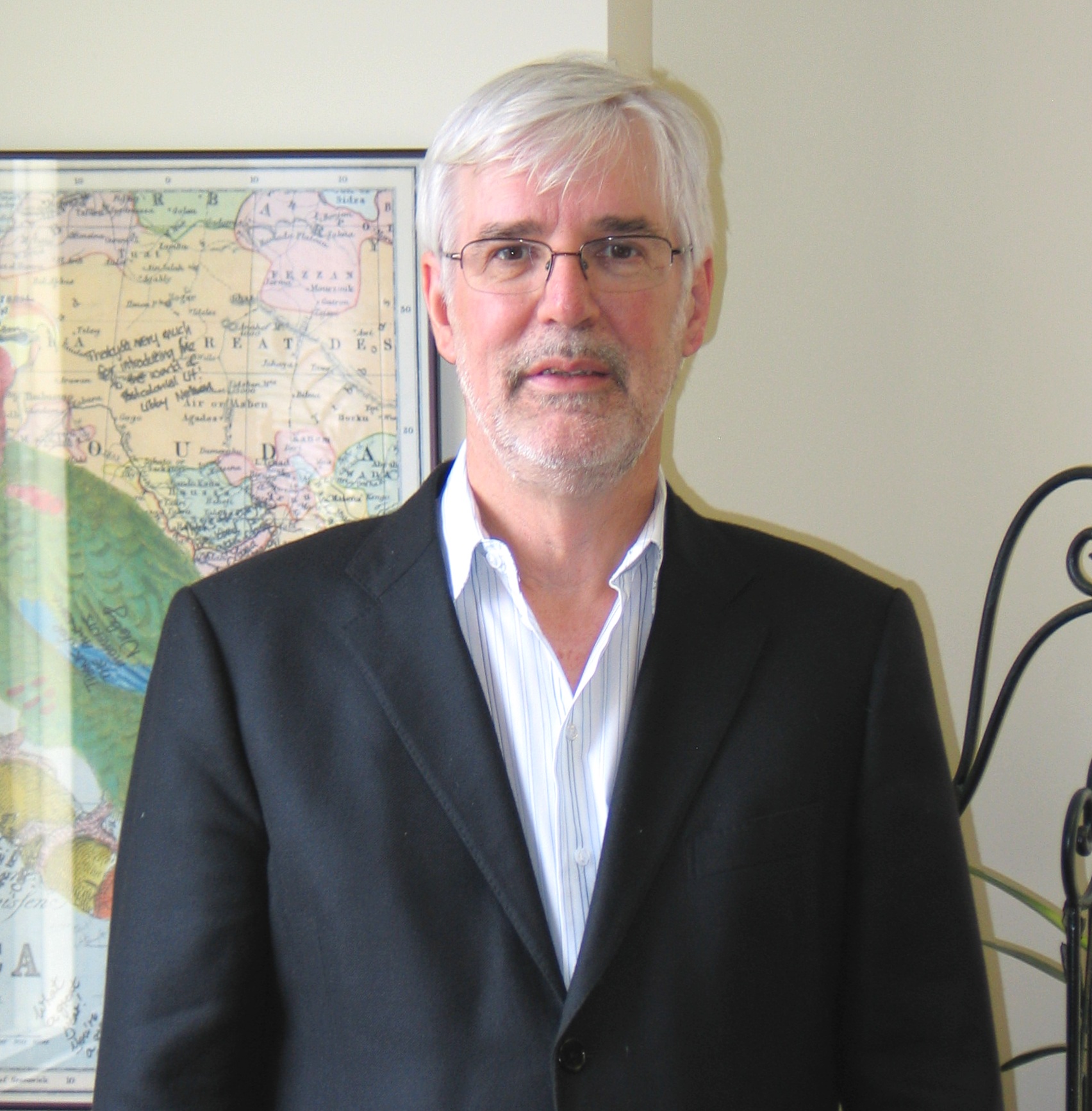Color headshot of Alan Bewell in a suit jacket and button down shirt. 