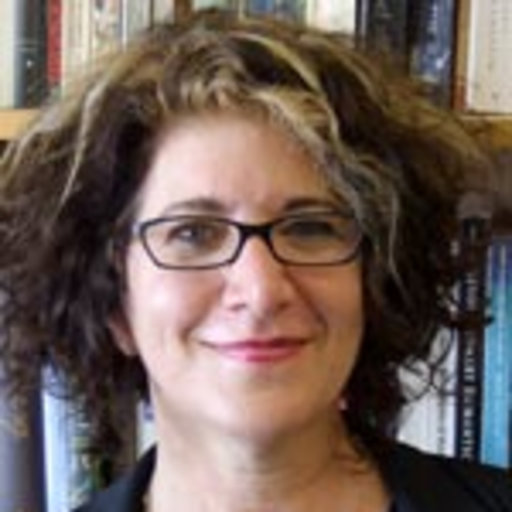 Anne Janowitz smiling in front of a bookcase. 