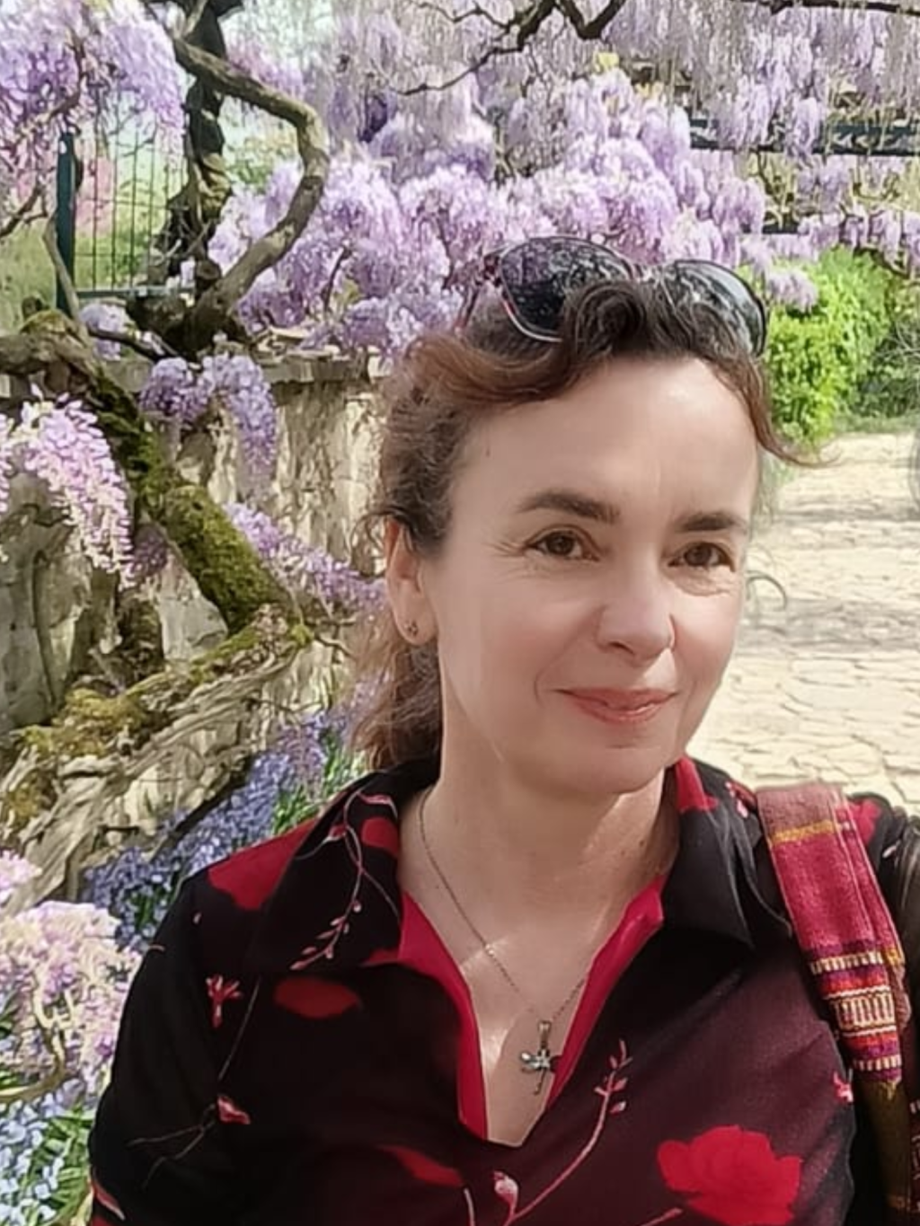 Color photograph of Astrid Wind in front of purple flowers.