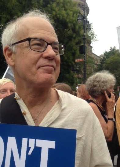 Color photograph of Bruce Robbins holding a sign.