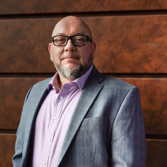 Color photograph of Chris Koenig-Woodyard in a pink shirt and grey suit jacket.