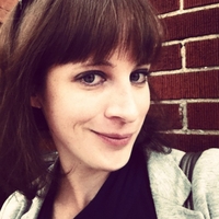 Color photo of Anne McCarthy in front of a brick wall.